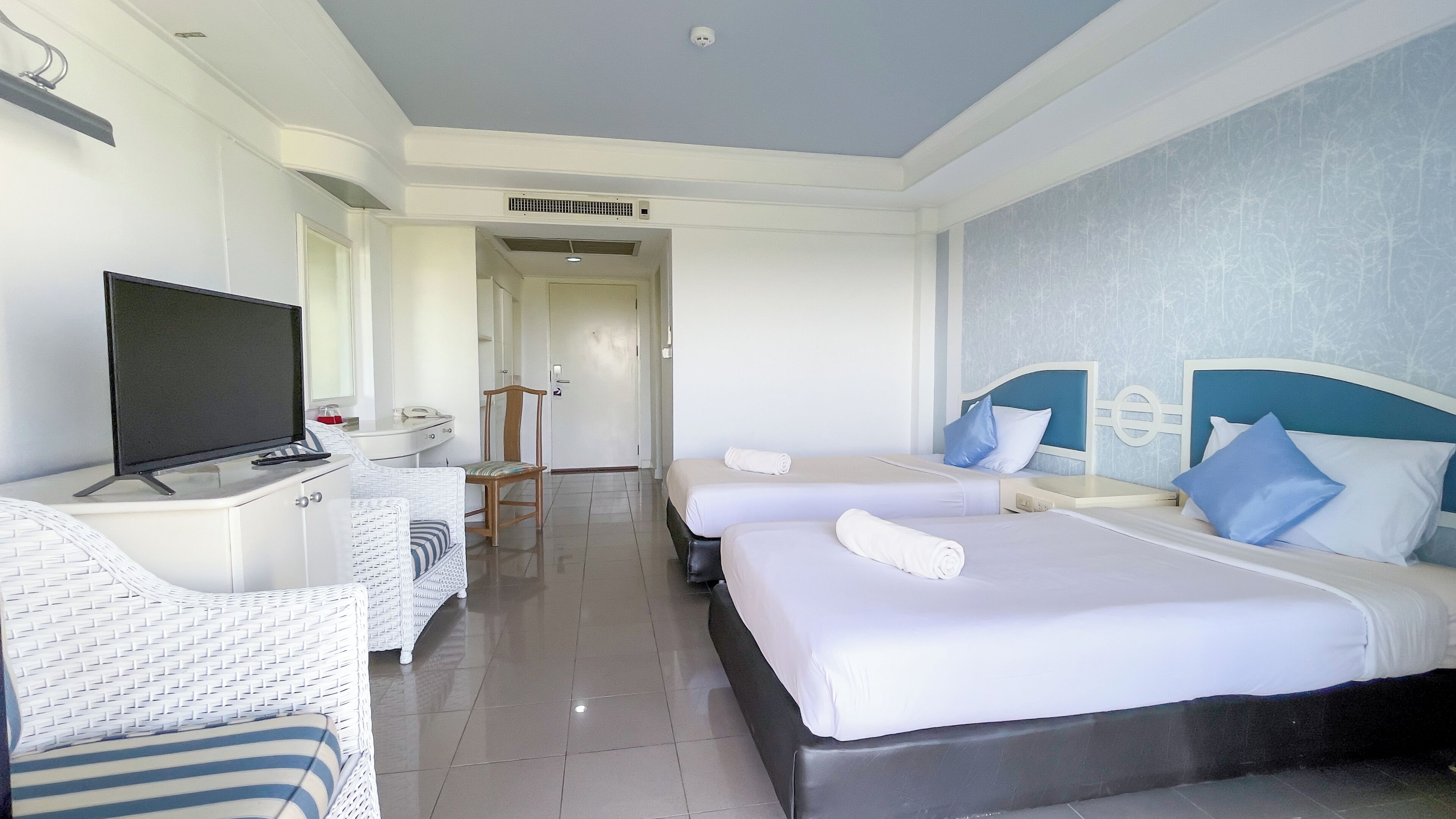A hotel room with two beds, a TV, a desk, and a chair.