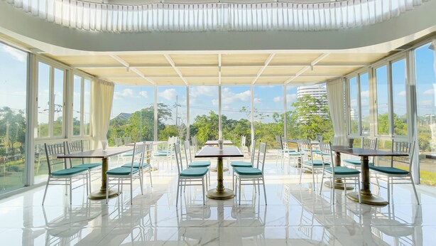 A spacious indoor dining area with large windows, a tiled floor, and green cushioned chairs. - Rua Rasada Express (Trang)