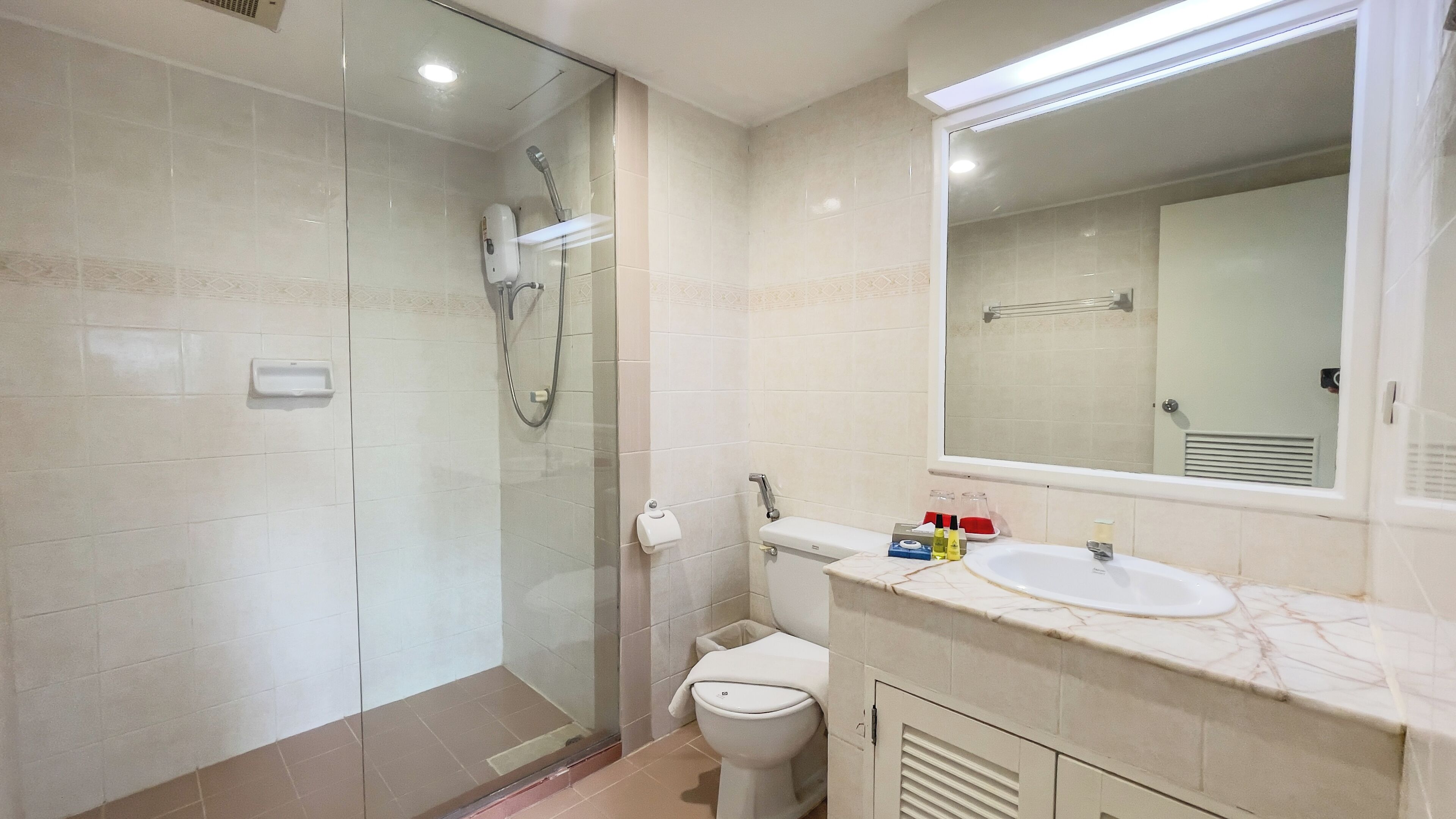 A modern bathroom with a glass-enclosed shower, a toilet, and a vanity with a mirror.