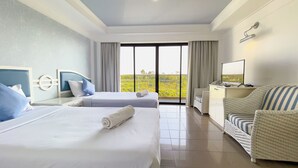 A hotel room with two beds, a desk, a chair, and a large window with a view of greenery. - Rua Rasada Express (Trang)