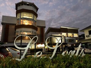 A hotel with a prominent tower and a large illuminated sign. - Hotel Le Lerts Living (Khon Kaen)
