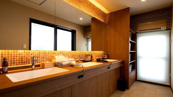 A modern bathroom with a wooden vanity, two sinks, a mirror, and a window.