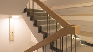 En moderne trappe med trægelændere og sorte metalspind.