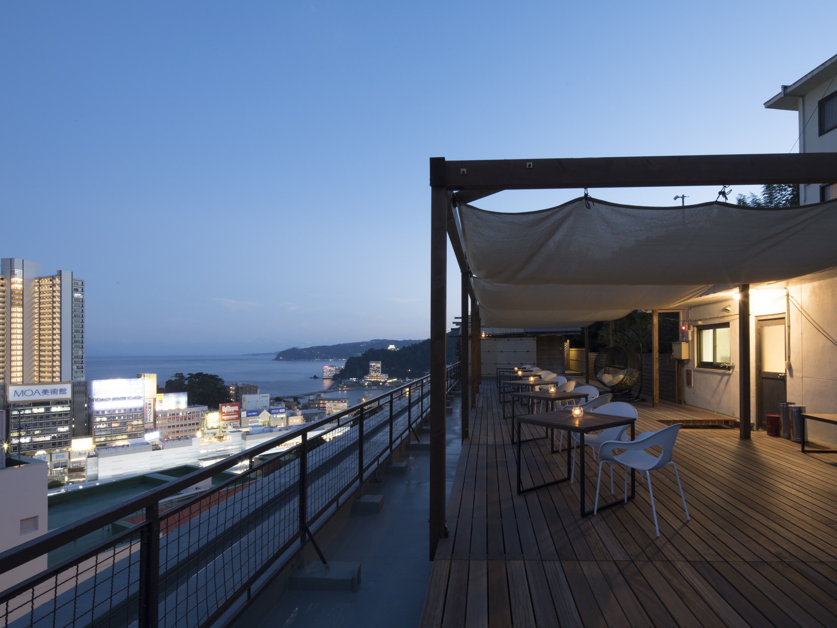 Una terraza con asientos al aire libre, con vistas a un paisaje urbano y al mar.