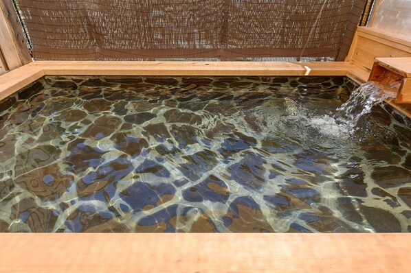 A clear pool with a wooden edge and a wooden structure at the far end.