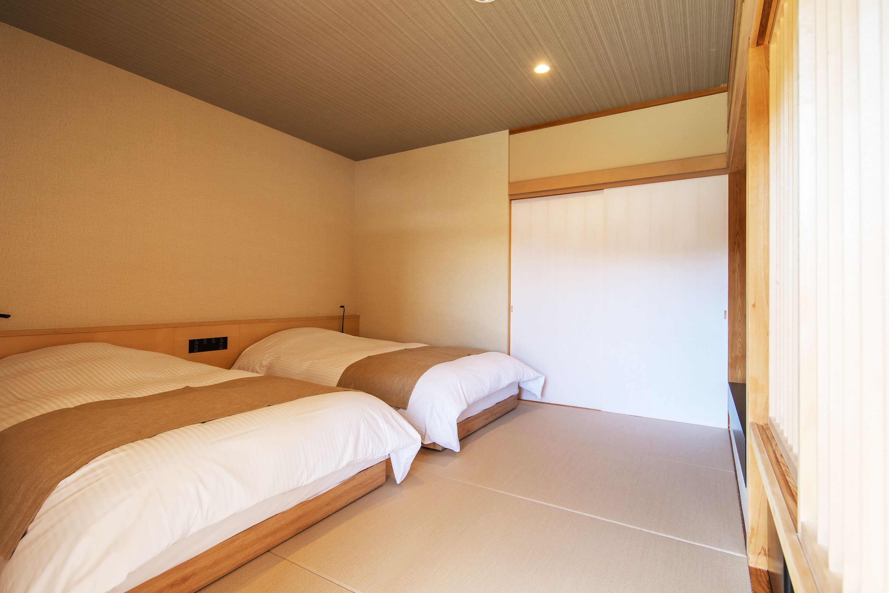 Una habitación con dos camas, cabeceros de madera y una puerta corredera.