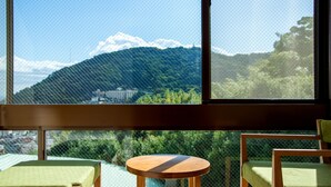 A room with a view of a mountain and a lake. There is a round wooden table and two green chairs. - Lectore Atami Koarashi (TKP Hotels & Resorts) (Atami)