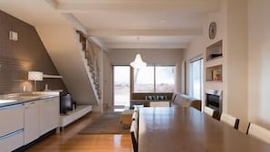 Una cocina moderna con comedor, una escalera y vistas al exterior.