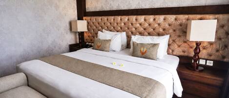 Une chambre d’hôtel avec un grand lit, deux tables de chevet, une tête de lit et un canapé.
