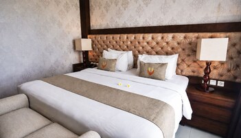 Hotellihuone, jossa on suuri sänky, kaksi yöpöytää, sängynpääty ja sohva.