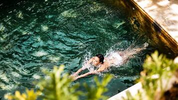Una persona nadando en una piscina con agua cristalina y borde de azulejos.
