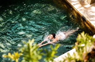 A person swimming in a pool with clear water and a tiled edge.