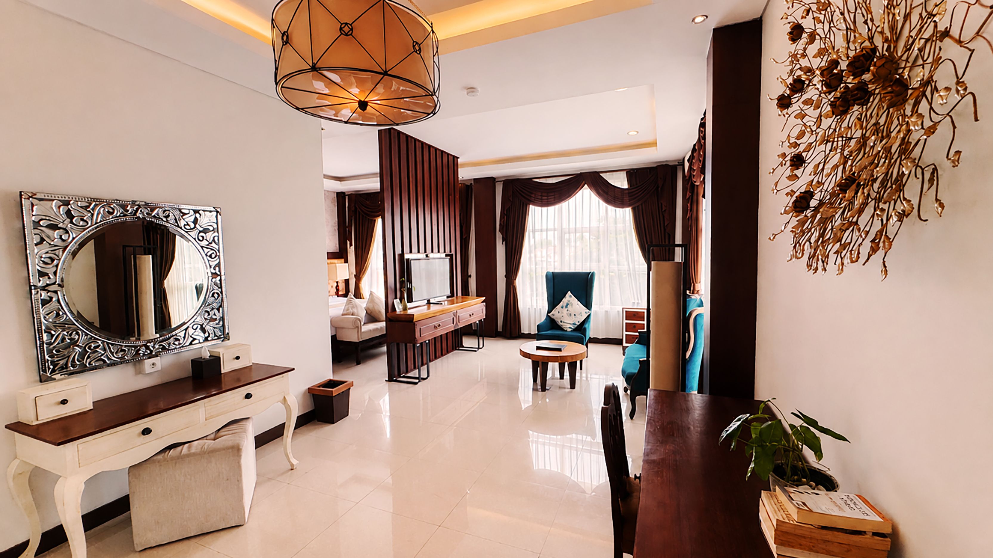 A modern hotel room with a large mirror, a desk, a sofa, and a dining area.