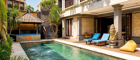 A swimming pool with lounge chairs, a statue, and a covered seating area.