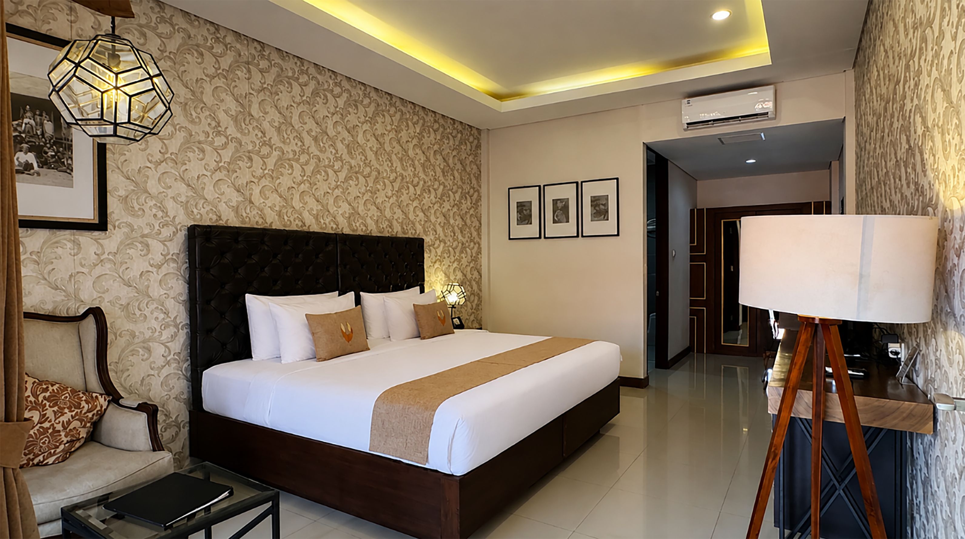 Una habitación de hotel moderna con una cama grande, una mesita de noche, una lámpara y un armario.