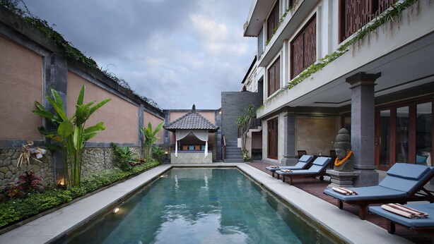 A swimming pool with lounge chairs, a small gazebo, and a statue. - The Visala Boutique Hotel (Keroboken Kelod)