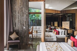 Habitación de hotel moderna con una cama grande, una zona de estar con sofá y sillones, y vista a zonas verdes.