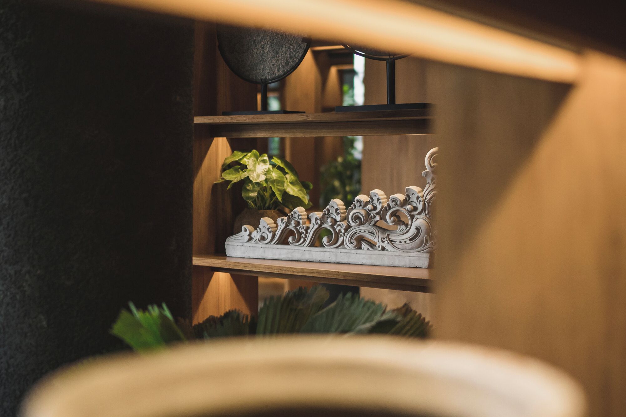 A shelf with decorative items including a plant and a metal sculpture.