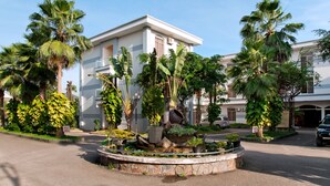 Un hotel con un patio central que cuenta con una maceta decorativa con diversas plantas y una fuente de piedra.