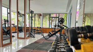 Un gimnasio con equipo de ejercicio, ventanas amplias y suelo de baldosas.