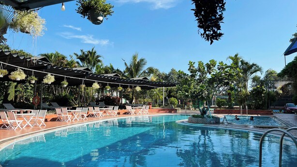Una piscina con sillas de descanso y plantas colgantes.
