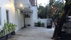 An outdoor area with a concrete floor, potted plants, and a black metal gate. - Menteng House (Jakarta)