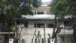 A multi-story building with a white facade, black gates, and a paved entrance area. - Menteng House (Jakarta)