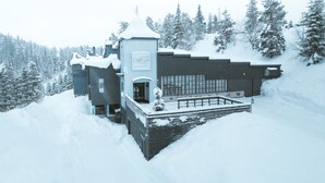 A modern ski resort building with a ski lift, surrounded by snow-covered trees.