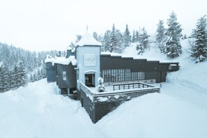 A modern ski resort building with a ski lift, surrounded by snow-covered trees.