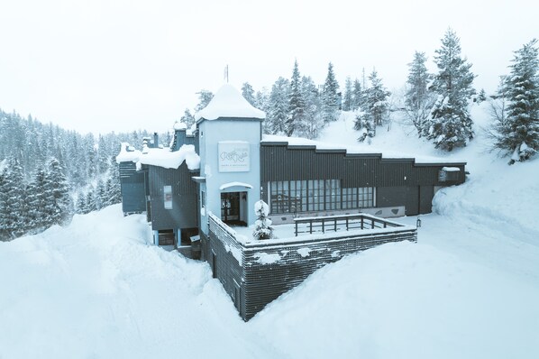 A modern ski resort building with a ski lift, surrounded by snow-covered trees.