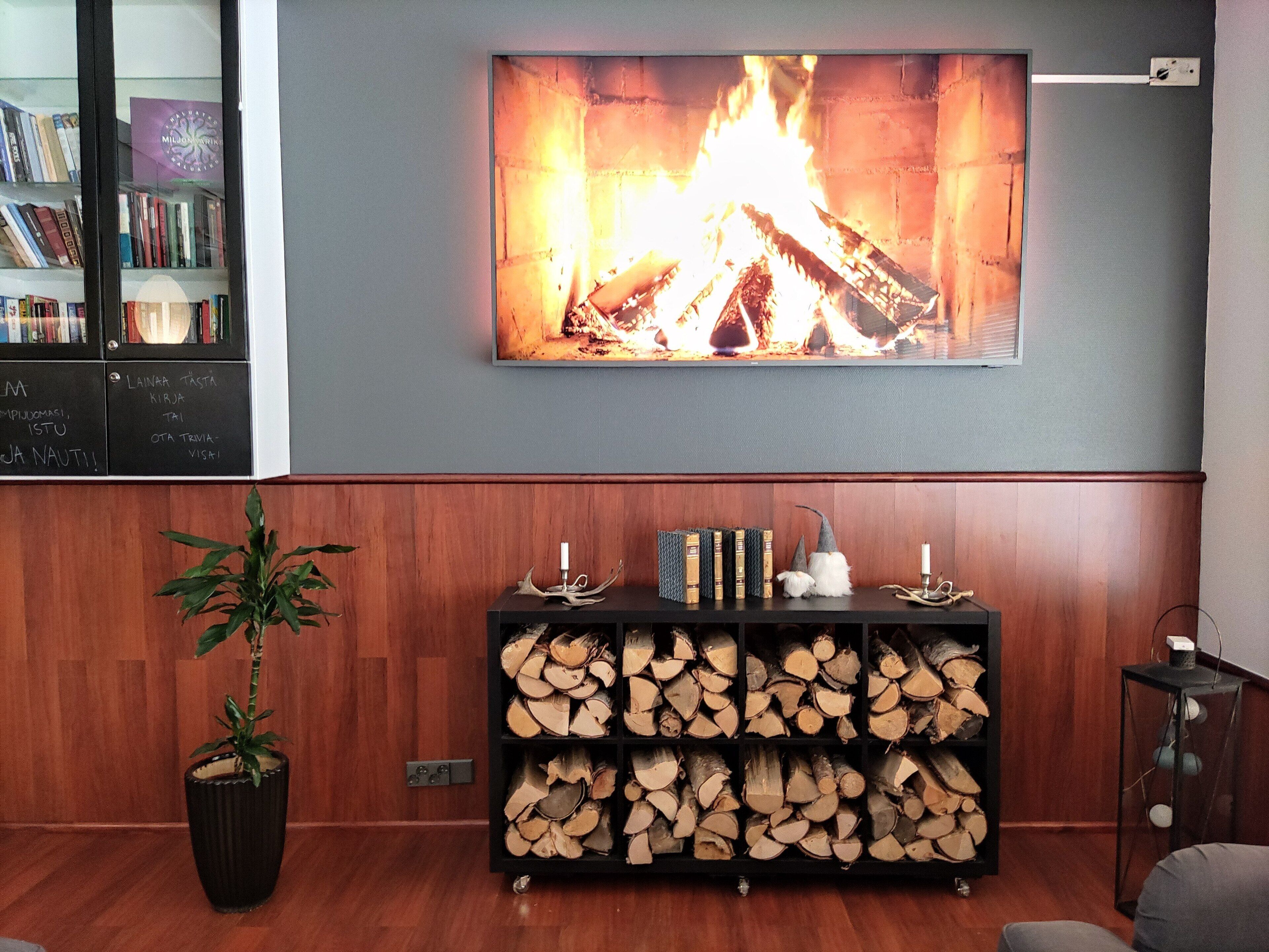 A room with a fireplace, a bookshelf, and a stack of firewood.