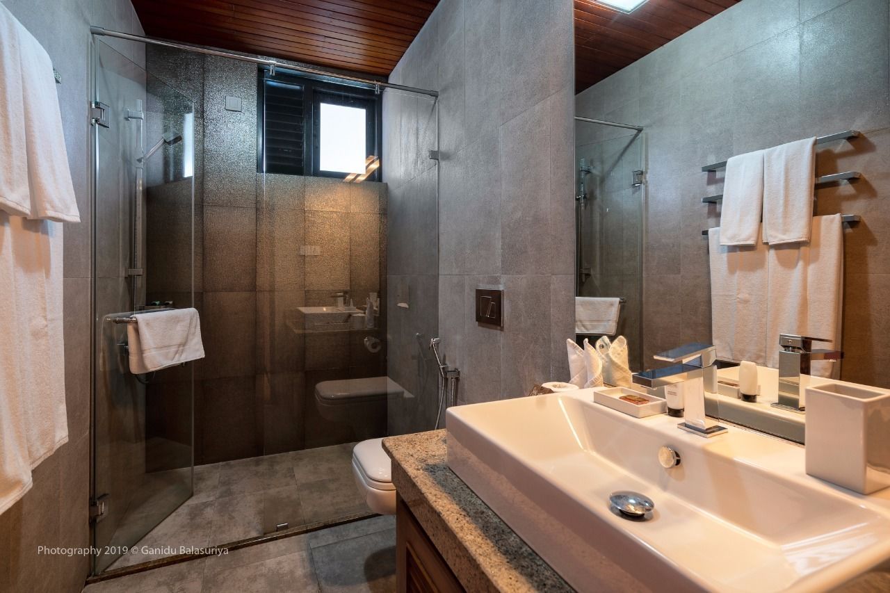A modern bathroom with a glass-enclosed shower, a large sink, and a toilet.
