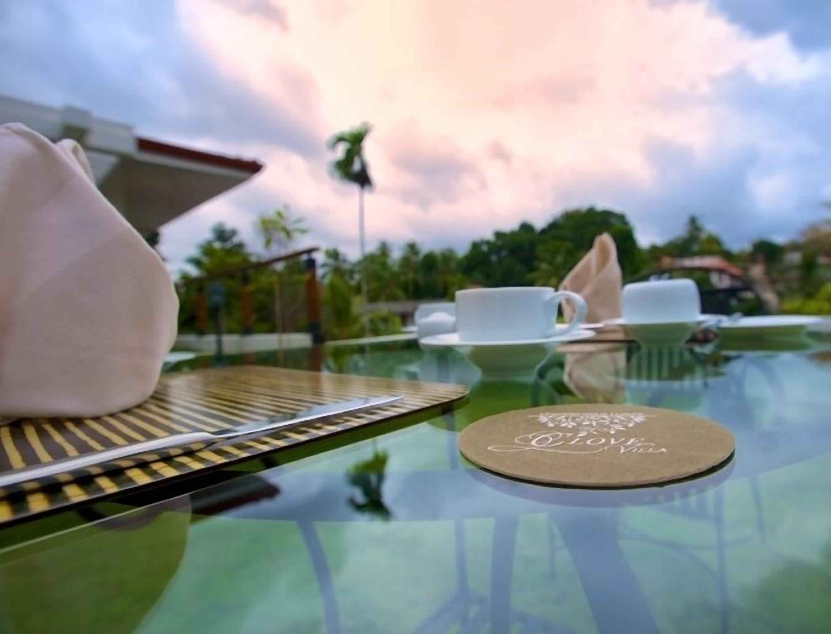 A table with a glass top, a white napkin, a white cup, and a saucer.