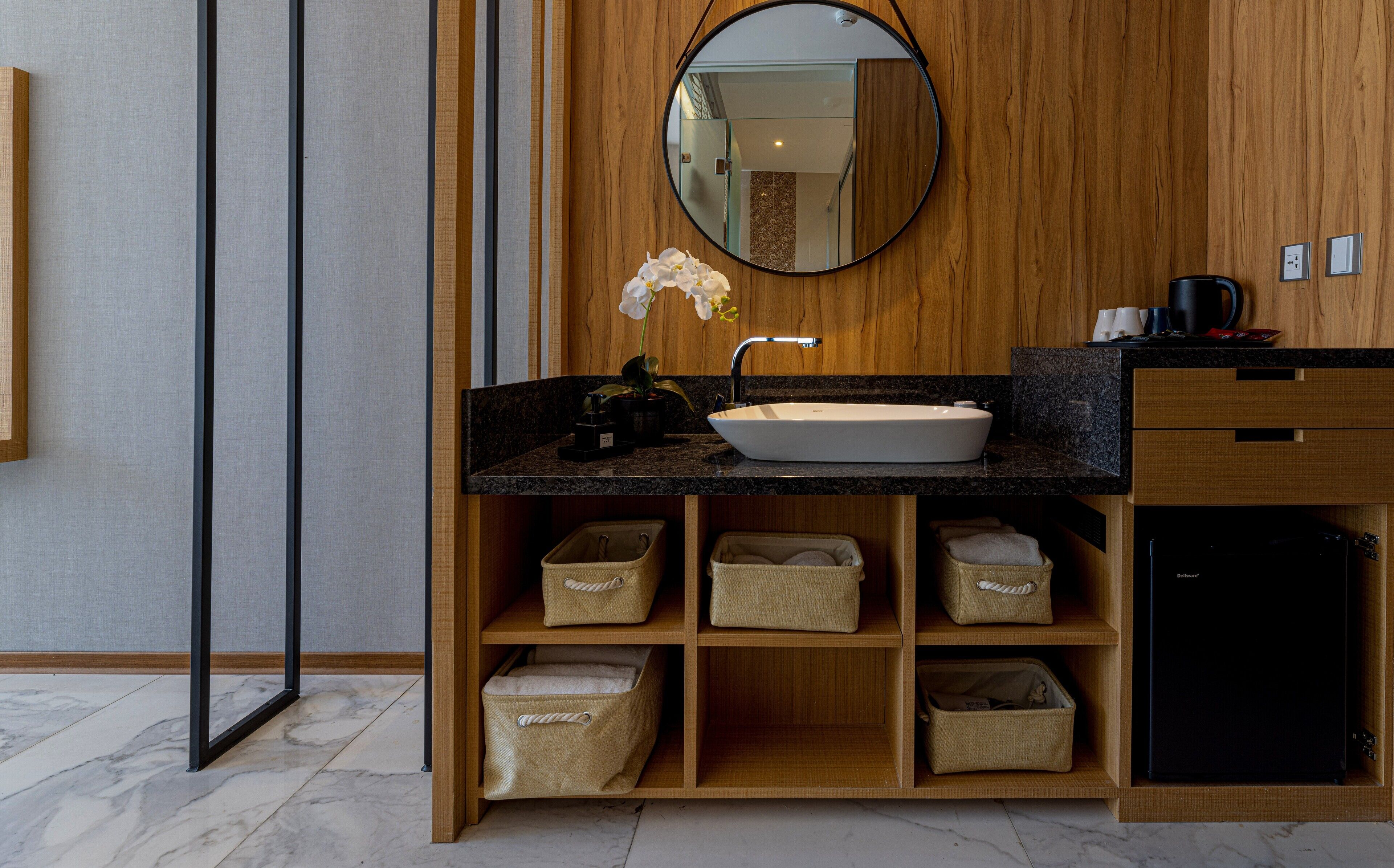 Un baño moderno con tocador de madera, lavamanos blanco y cajones de almacenamiento integrados.