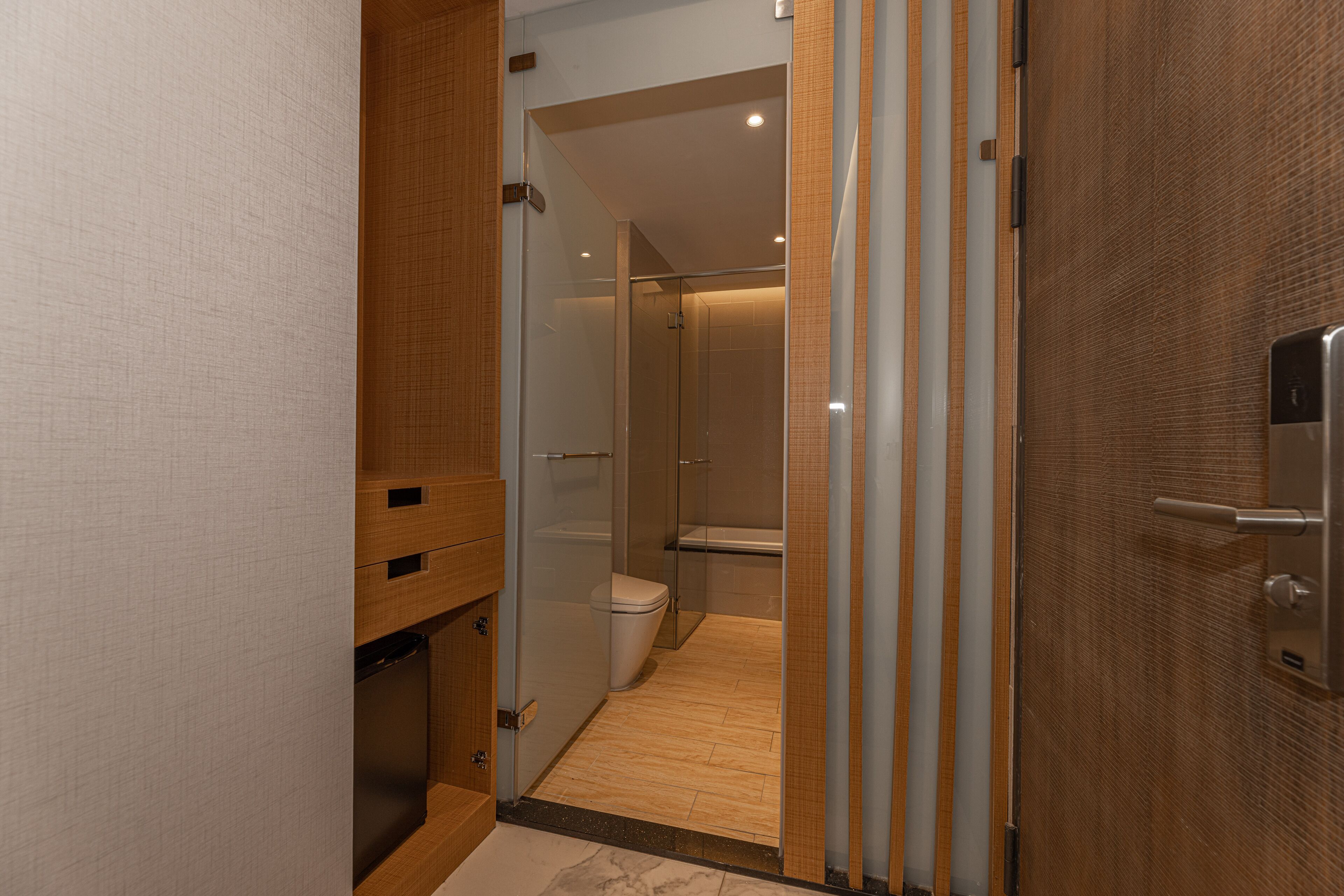 A modern bathroom with a glass shower enclosure, a toilet, and a wooden vanity.