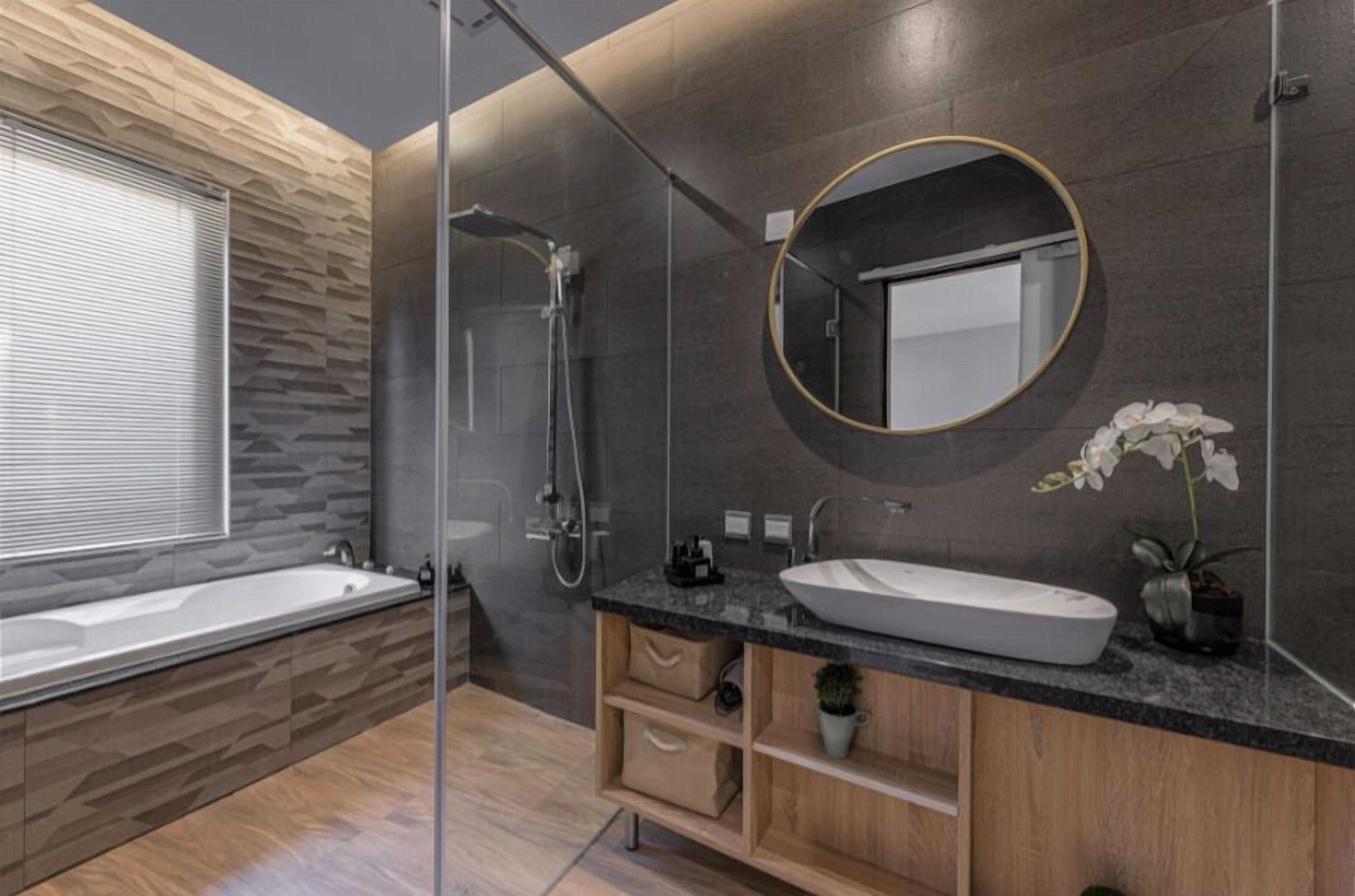 Un baño moderno con una bañera independiente, un espejo grande y un mueble de tocador con lavabo y espacio de almacenamiento.