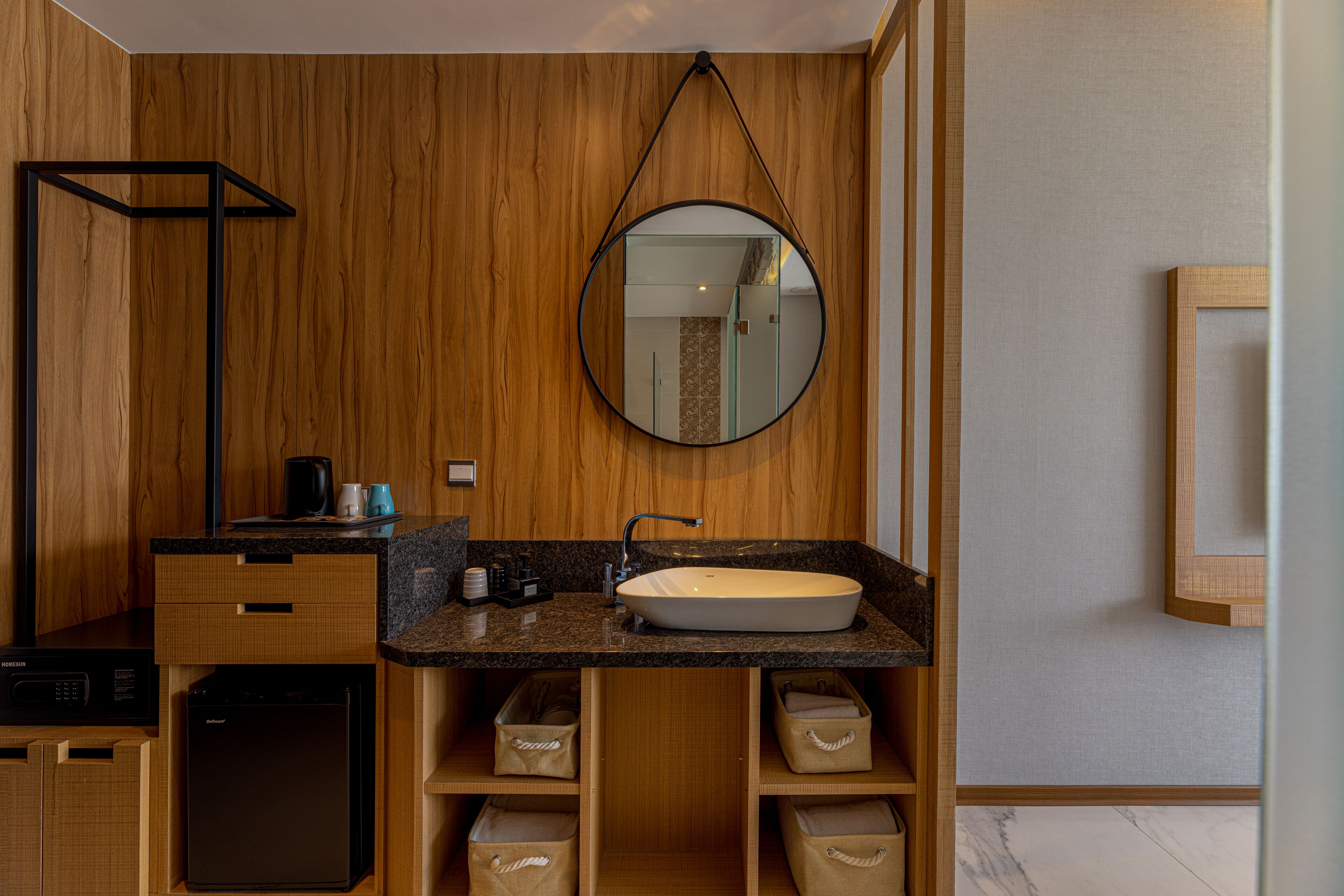 Une salle de bain moderne avec un lambris en bois, un miroir rond, un lavabo et des rangements intégrés.