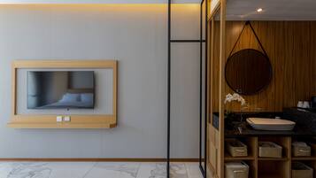 Un baño moderno con tocador de madera, un espejo redondo y televisor integrado.