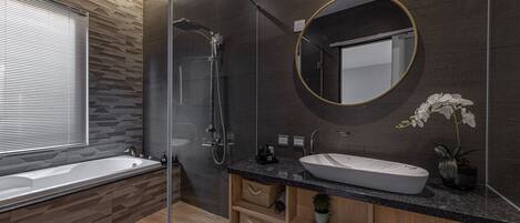 Uma casa de banho moderna com uma banheira grande, área de duche separada e toucador com lavatório e espelho.