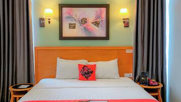 A hotel room with a large bed, two bedside tables, a headboard, a framed abstract painting, and two wall-mounted lamps.