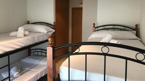 Une chambre de dortoir équipée de deux lits superposés, chacun ayant une tête de lit en bois et une structure en métal.