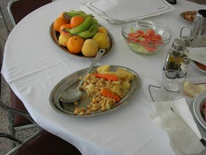 Een tafel met een bord eten, een saladekom en een schaal fruit.