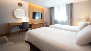 A hotel room with two beds, a desk, a chair, a TV, and a large window with curtains. - Ulsan City Hotel (Ulsan)