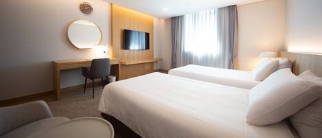 A hotel room with two beds, a desk, a chair, a TV, and a large window with curtains.