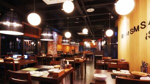 A restaurant interior with wooden tables, hanging pendant lights, and a visible menu board. - Ulsan City Hotel (Ulsan)