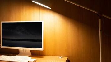 Un ordinateur de bureau avec un écran affichant une scène nocturne, un clavier, une souris et une lampe de bureau.
