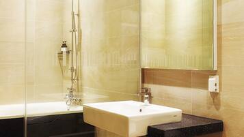 A modern bathroom with a glass-enclosed shower, a white sink, and a large mirror.