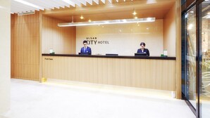 A reception desk at ULSAN CITY HOTEL with a wooden finish and modern lighting. - Ulsan City Hotel (Ulsan)