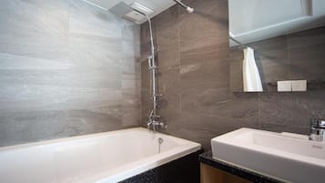 A modern bathroom with a bathtub, two sinks, and a shower.