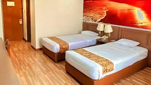 Een hotelkamer met twee bedden, een groot raam en uitzicht op een zonsondergang.
